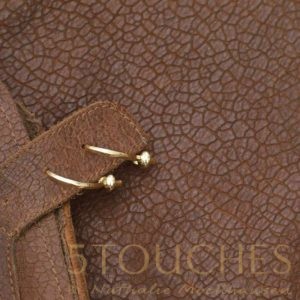 The 5Touches Earrings on brown leather.