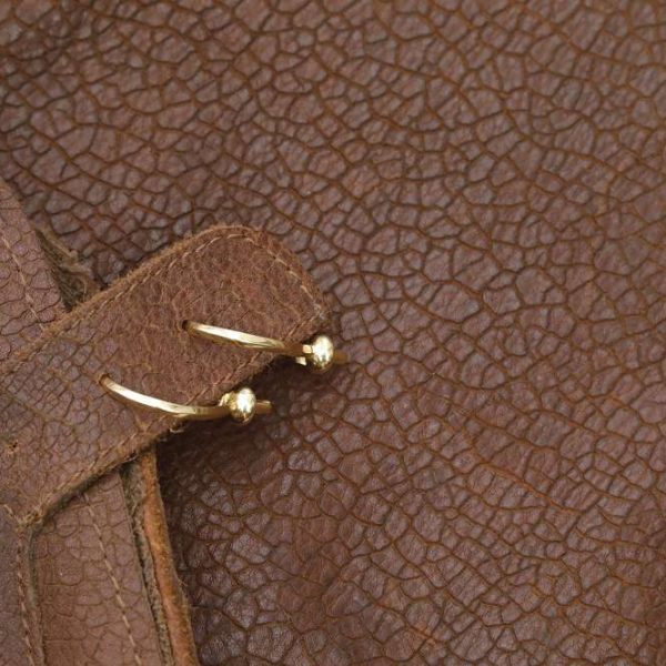 The 5Touches Earrings on brown leather.